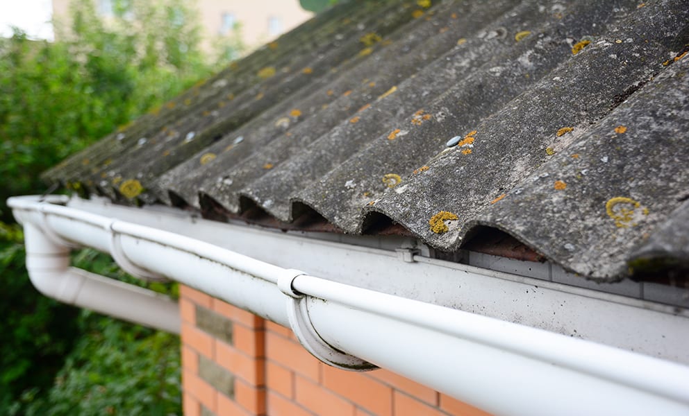 house,asbestos,roof,with,close,up,gutter,holder,and,plastic